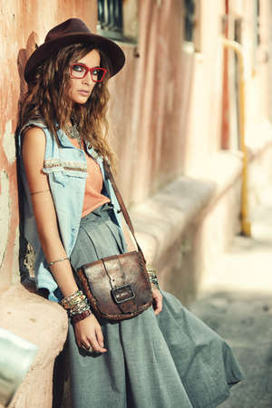 Denim style. Sexual young woman posing in jeans clothes on a street. Beauty, fashionable look. Boho style clothes and accessories.の写真素材
