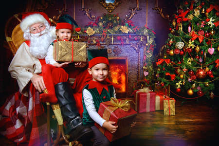 Santa Claus and the elves children with gift boxes. Miracles on Christmas.の写真素材
