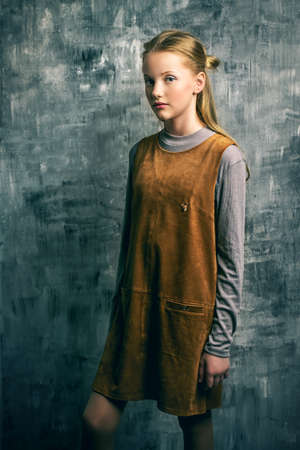 Teen fashion. Portrait of a cute girl teenager standing by a grunge wall.の写真素材