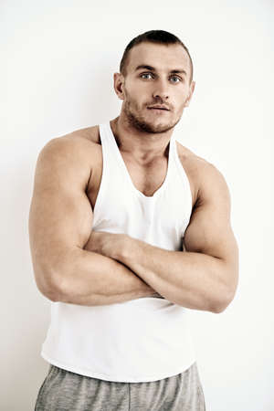 Portrait of a handsome athletic man posing in casual clothes in white room. Health and sports. Bodybuilding.の写真素材