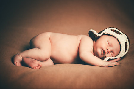 Portrait of a cute newborn baby sleeping in a pilot's hat.