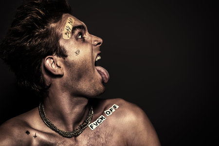 Bad boy concept. A portrait of a bad guy demonstrating antisocial behavior, rudeness and aggression. Rocker, punk.の写真素材