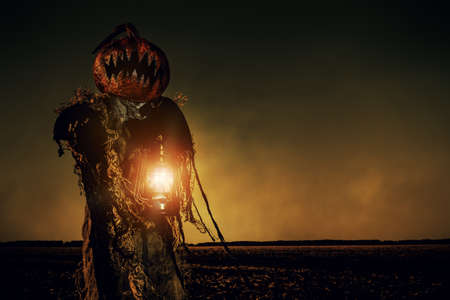 Halloween legend. Portrait of Jack-lantern with a pumpkin on his head standing in the field as a scarecrow.の写真素材
