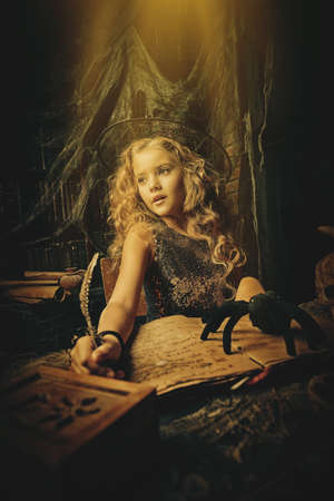 Beautiful charming little witch conjures in her lair. Halloween.の写真素材