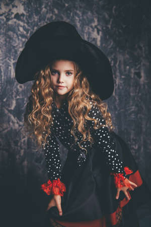 Beautiful child girl in a costume of a witch over grunge background. Halloween party.の写真素材