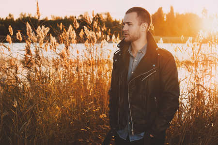 Handsome young man in the autumn park on a sunset. Seasonal fashion.の写真素材