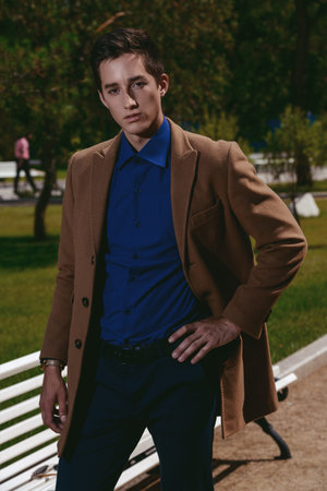 Elegant young man posing in stylish clothes in a summer park. Outdoor fashion. Business style.