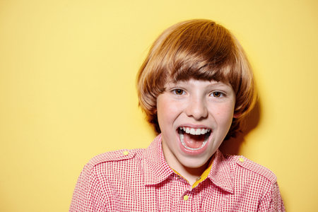 Portrait of a happy smiling boy over bright yellow background. Kid's fashion.