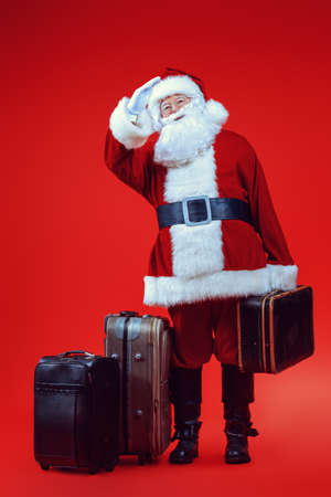 Christmas, tourist trip concept. Santa Claus with suitcases is going to travel around the planet. Christmas time. Time for miracles. Copy space.の写真素材