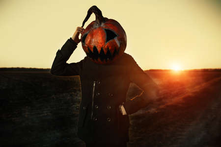 Modern Jack-lantern with a pumpkin on his head stands in a field. Halloween concept.の写真素材