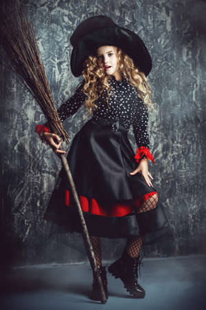 Beautiful child girl in a costume of a witch over grunge background. Halloween party.の写真素材