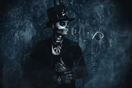 A man with a skull makeup dressed in a tail-coat and a top-hat. Baron Saturday. Baron Samedi. Dia de los muertos. Day of The Dead. Halloween.の写真素材
