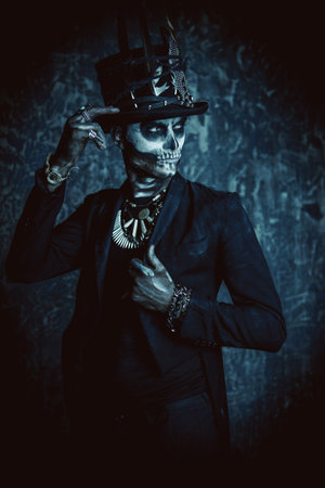 A man with a skull makeup dressed in a tail-coat and a top-hat. Baron Saturday. Baron Samedi. Dia de...