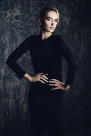 Elegant blonde young woman wearing black fitting dress. Beauty, fashion concept. Studio shot.の写真素材