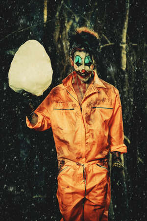 Bloodthirsty clown man in a night forest with a candy-floss. Halloween. Horror.の写真素材