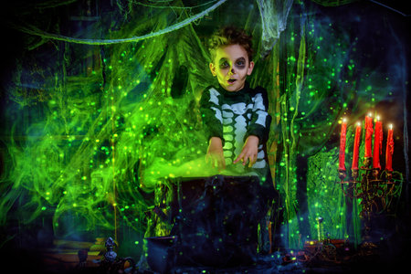 Happy Halloween. Funny child boy in a costume of skeleton cooks a magic potion in a witch's lair.