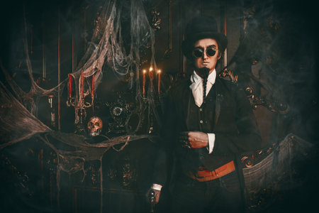 Halloween. Elegant and mysterious gloomy man aristocrat in a black tailcoat and top-hat stands in an...