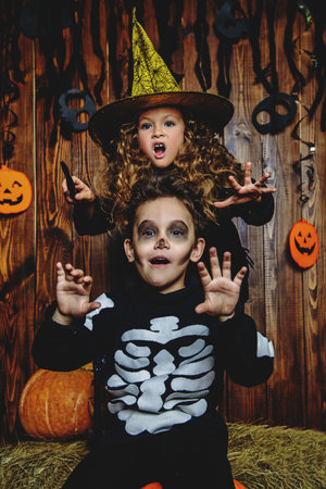 Portrait of a cute funny kids posing with pumpkins on a hay. Happy Halloween!の写真素材