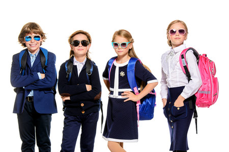 Group of modern children posing in school uniform and sunglasses. School fashion. Isolated over...