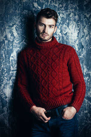 Portrait of a handsome young man in a warm sweater. Autumn, winter clothes. Male beauty, fashion.の写真素材
