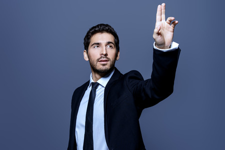 Contemporary businessman hand touching empty virtual screen. Studio shot. Copy space. Modern business technologies concept.の写真素材