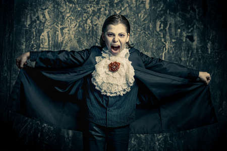 Portrait of a boy dressed in a costume of a vampire over grunge background. Halloween party.の写真素材