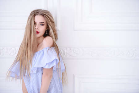 Beauty, fashion portrait. Charming blonde girl in a pale blue dress in a white luxurious apartments.の写真素材