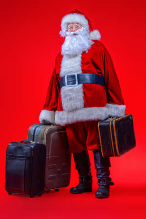 Christmas, tourist trip concept. Santa Claus with suitcases is going to travel around the planet. Christmas time. Time for miracles. Copy space.の写真素材