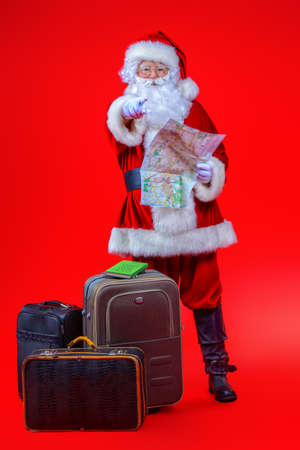 Christmas, tourist trip concept. Santa Claus with suitcases is going to travel around the planet. Christmas time. Time for miracles. Copy space.の写真素材