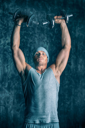 Muscular sportsman bodybuilder doing exercises with dumbbells. Health and sports concept.の写真素材