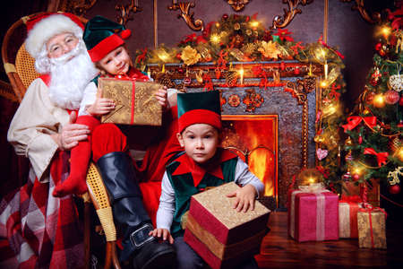 Santa Claus and the elves children with gift boxes. Miracles on Christmas.の写真素材