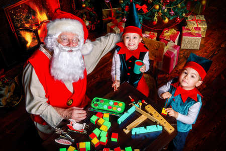 Santa Claus and the elves make gifts for children at Christmas. Workshop of Santa Claus. Christmas concept.の写真素材