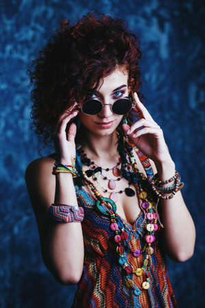 Beautiful bright woman with curly foxy hair wears a dress and beads in boho style. Ethnic style in clothes.の写真素材
