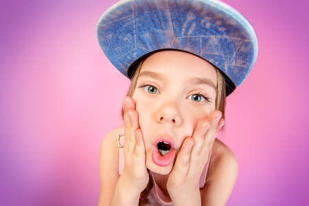 Close-up portrait of a funny emotional girl making faces at camera. Studio shot over pink background.の写真素材