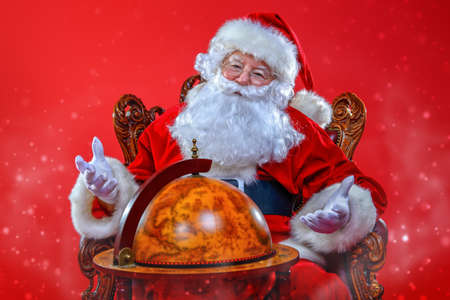Christmas, tourist trip concept. Santa Claus sitting on his armchair and making plans of travelling around the planet. Christmas time. Time for miracles. Copy space. の写真素材