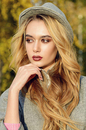 Beautiful fashion model posing in the autumn park. Autumn seasonal fashion.