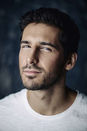 Close-up portrait of a handsome young man wearing white t-shirt. Studio shot. Men's beauty and health.の写真素材