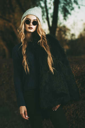 Autumn fashion shot. Trendy young woman in warm clothes posing in the autumn park. Youth style.の写真素材