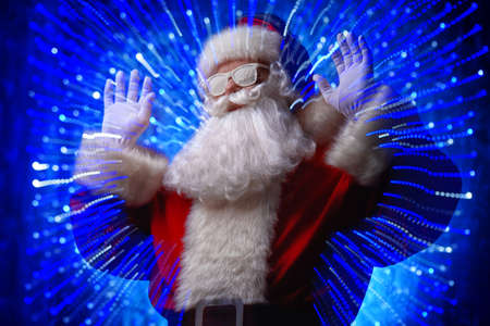 DJ Santa Claus in snowy glasses and headphones. Christmas songs and music. Disco lights in the background.の写真素材
