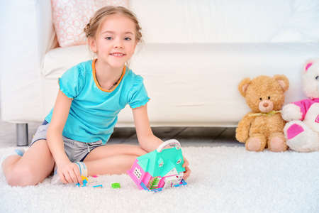 Happy girl child spending time at home, playing with a toy house. Free time, activity and hobby. Family concept. の写真素材