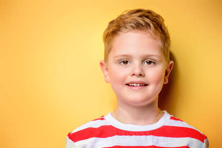 Portrait of a cute boy over bright yellow background. Clothes for children. Kid's fashion.の写真素材