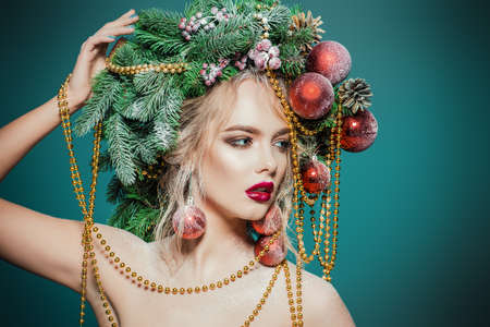 Portrait of a beautiful young woman with christmas tree in hairstyle decorated with beads and balls. Holiday make-up. Beauty, fashion.の写真素材