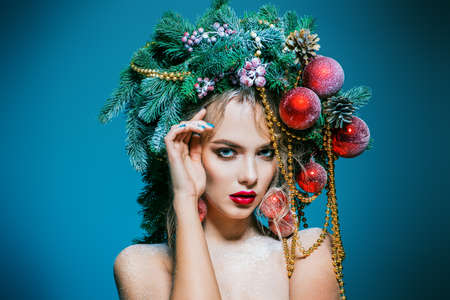 Portrait of a beautiful young woman with christmas tree in hairstyle decorated with beads and balls. Holiday make-up. Beauty, fashion.の写真素材