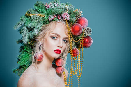 Portrait of a beautiful young woman with christmas tree in hairstyle decorated with beads and balls. Holiday make-up. Beauty, fashion.の写真素材