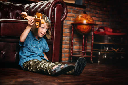 Cute dreamer boy playing with toy airplane at home. Childhood. Fantasy, imagination. の写真素材