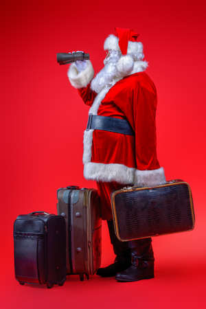 Christmas, tourist trip concept. Santa Claus with suitcases is going to travel around the planet. Christmas time. Time for miracles. Copy space. の写真素材
