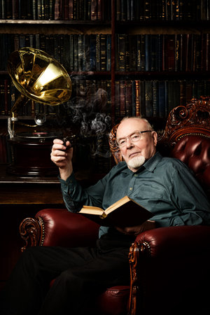 An old intelligent man listens to an old gramophone in his library. Retirement. の写真素材