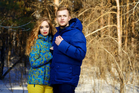 Couple of young people in winter clothes in the park. Winter fashion. Down jacket.の写真素材
