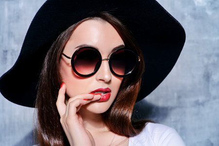 Close-up portrait of a hipster girl wearing hat and round sunglasses. Beauty, cosmetics.