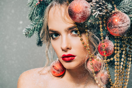 Close-up portrait of a beautiful young woman with christmas tree in hairstyle decorated with beads and balls. Holiday make-up. Beauty, fashion.の写真素材